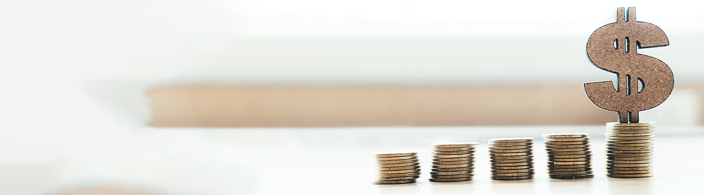 a stack of coins with a wooden dollar symbol on top of a desk
