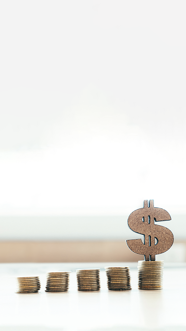 a stack of coins with a wooden dollar symbol on top of a desk